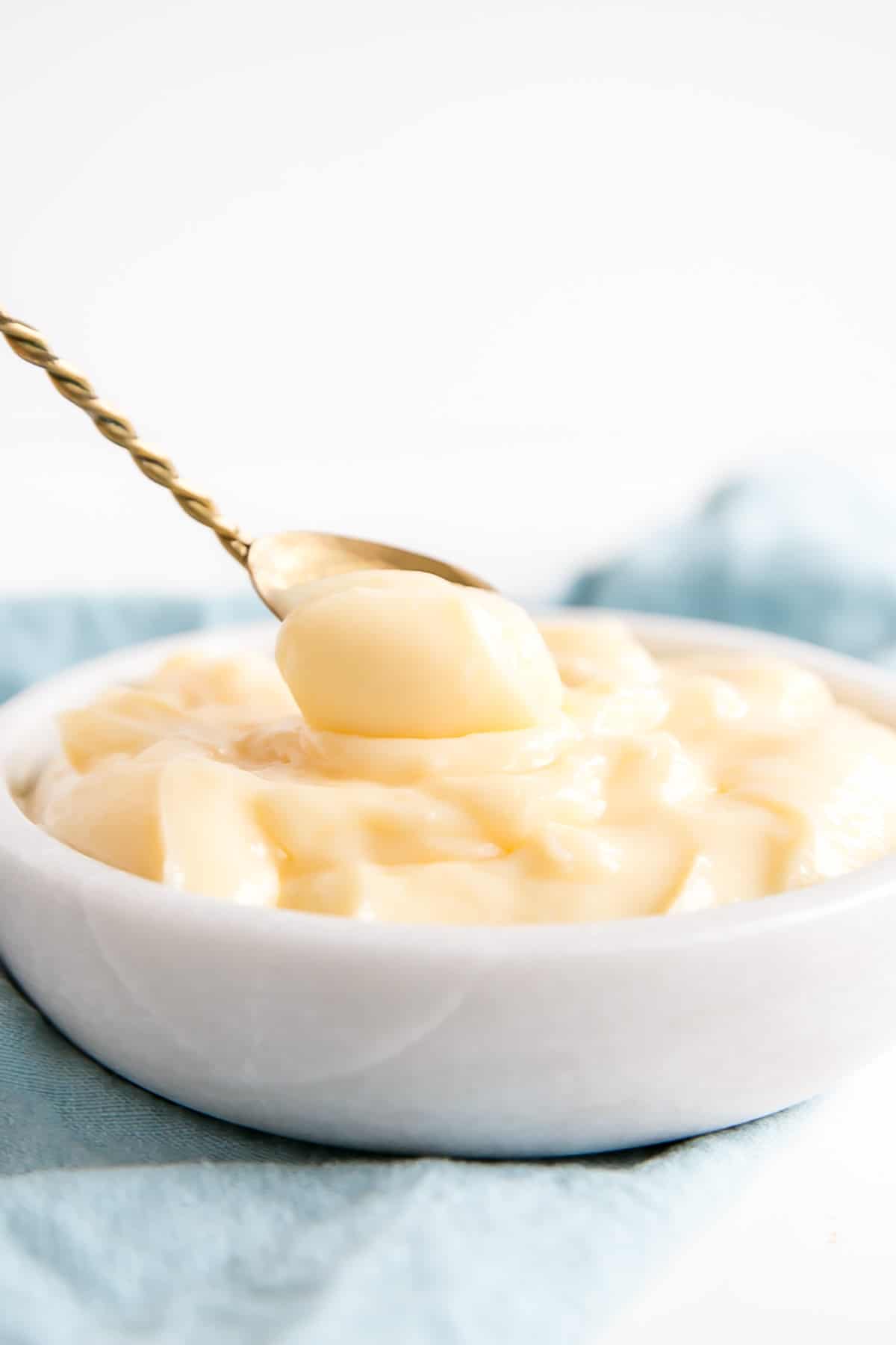 A spoon dipping into the bowl of pastry cream.