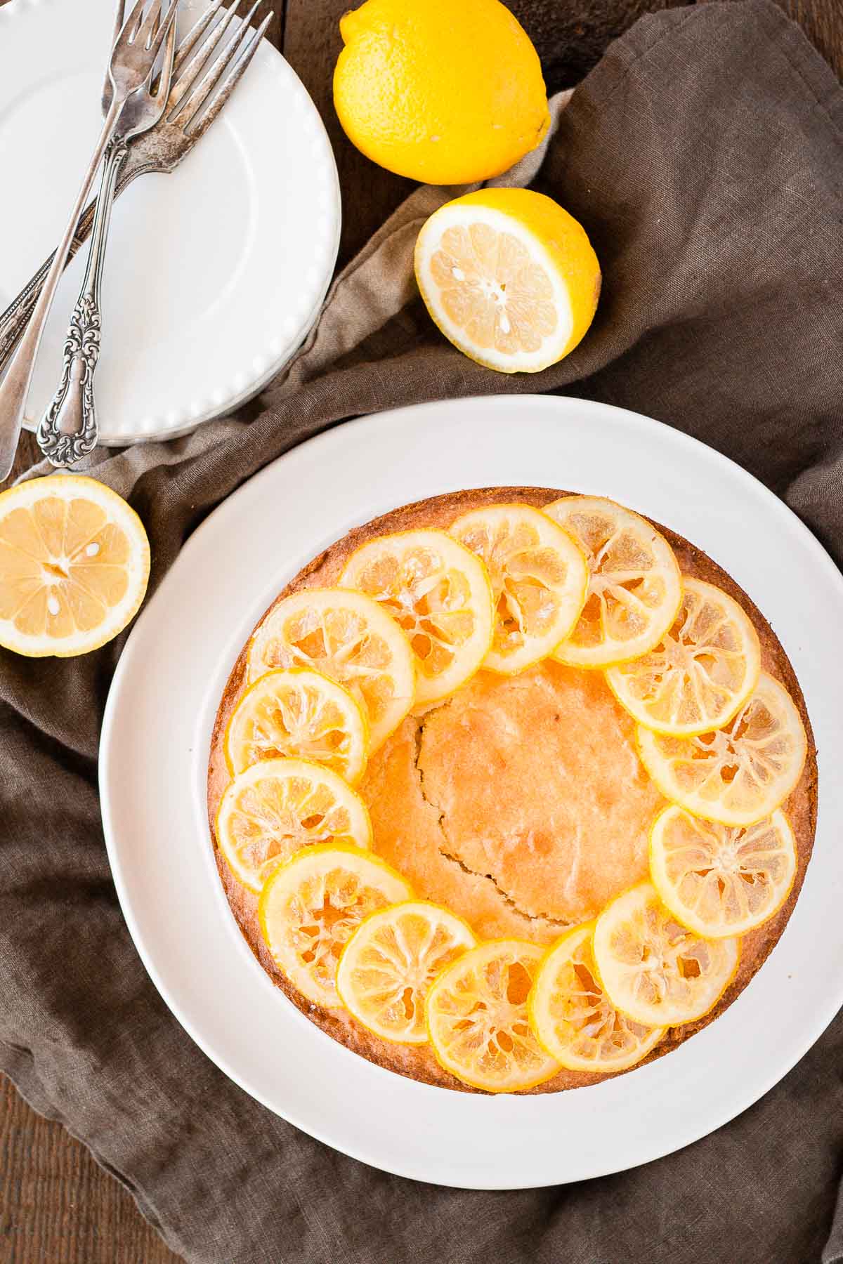 Overhead shot of the cake on a white plate with cut lemons beside it.