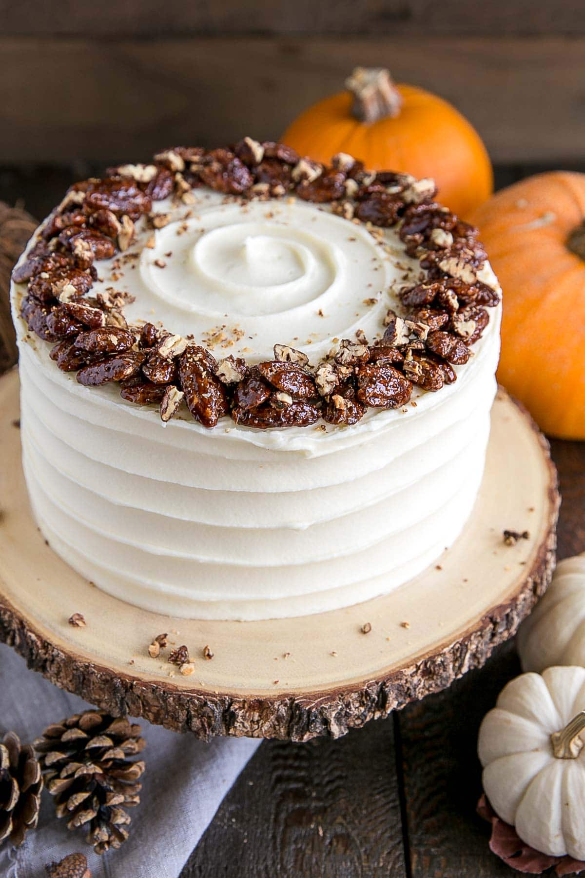 Cake on a rustic cake stand with pumpkins in the background.