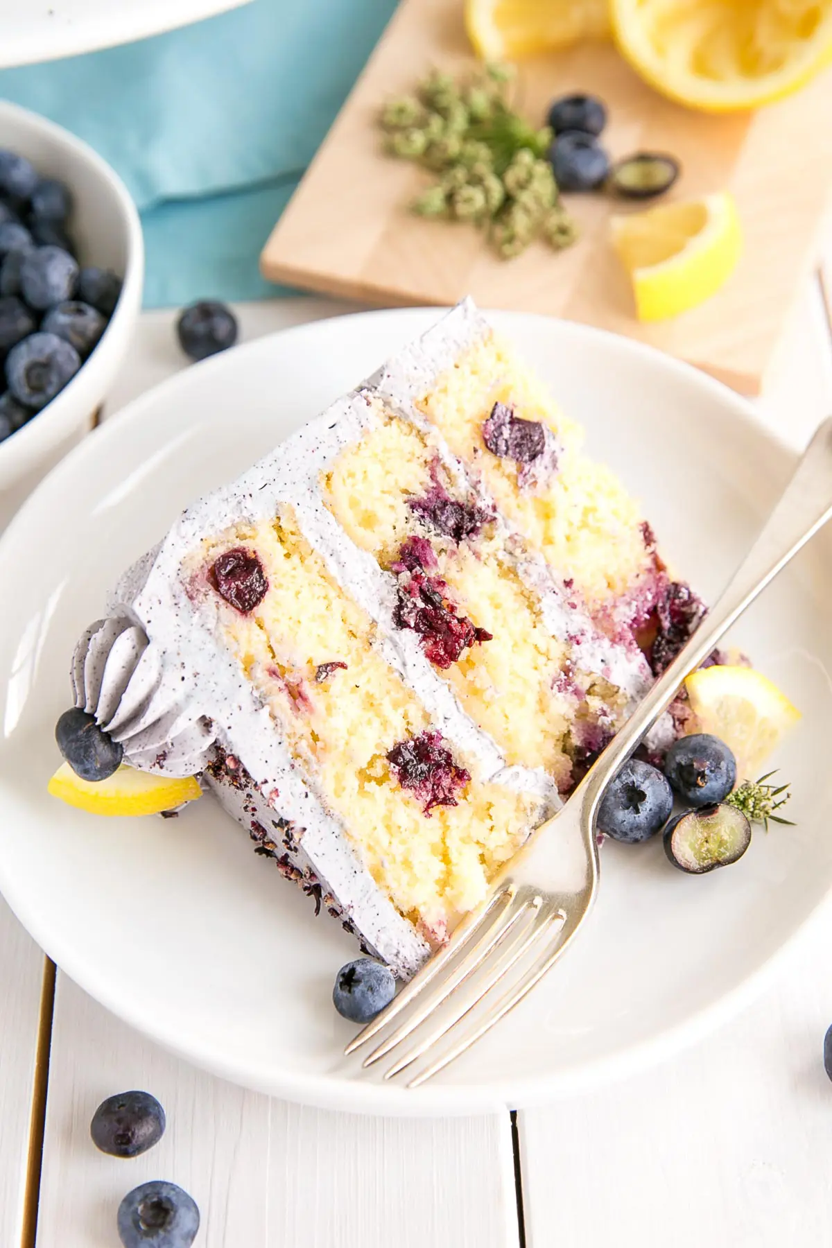 Slice of lemon blueberry cake on a plate with blueberry buttercream