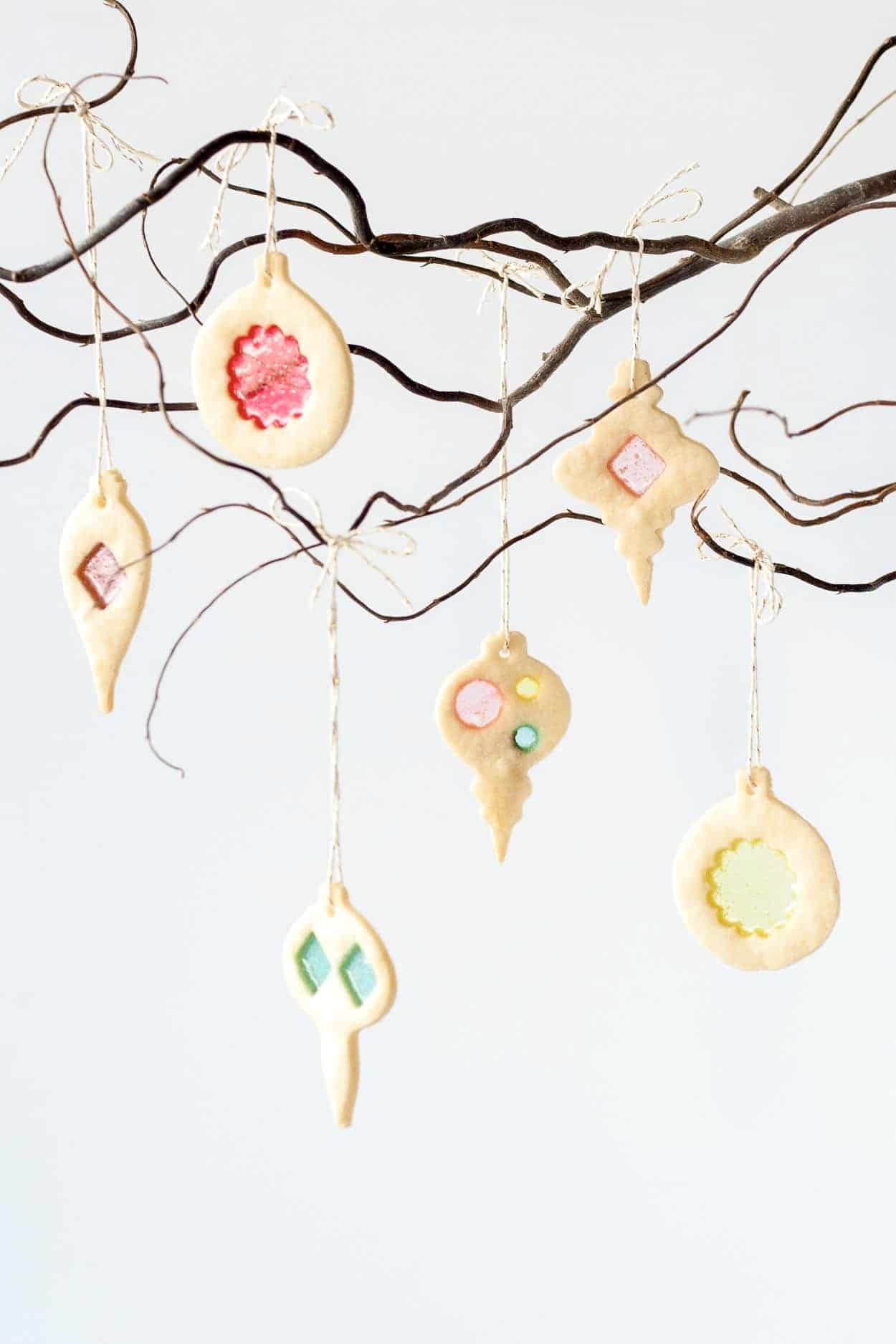Stained glass cookie ornaments hanging from a tree branch.