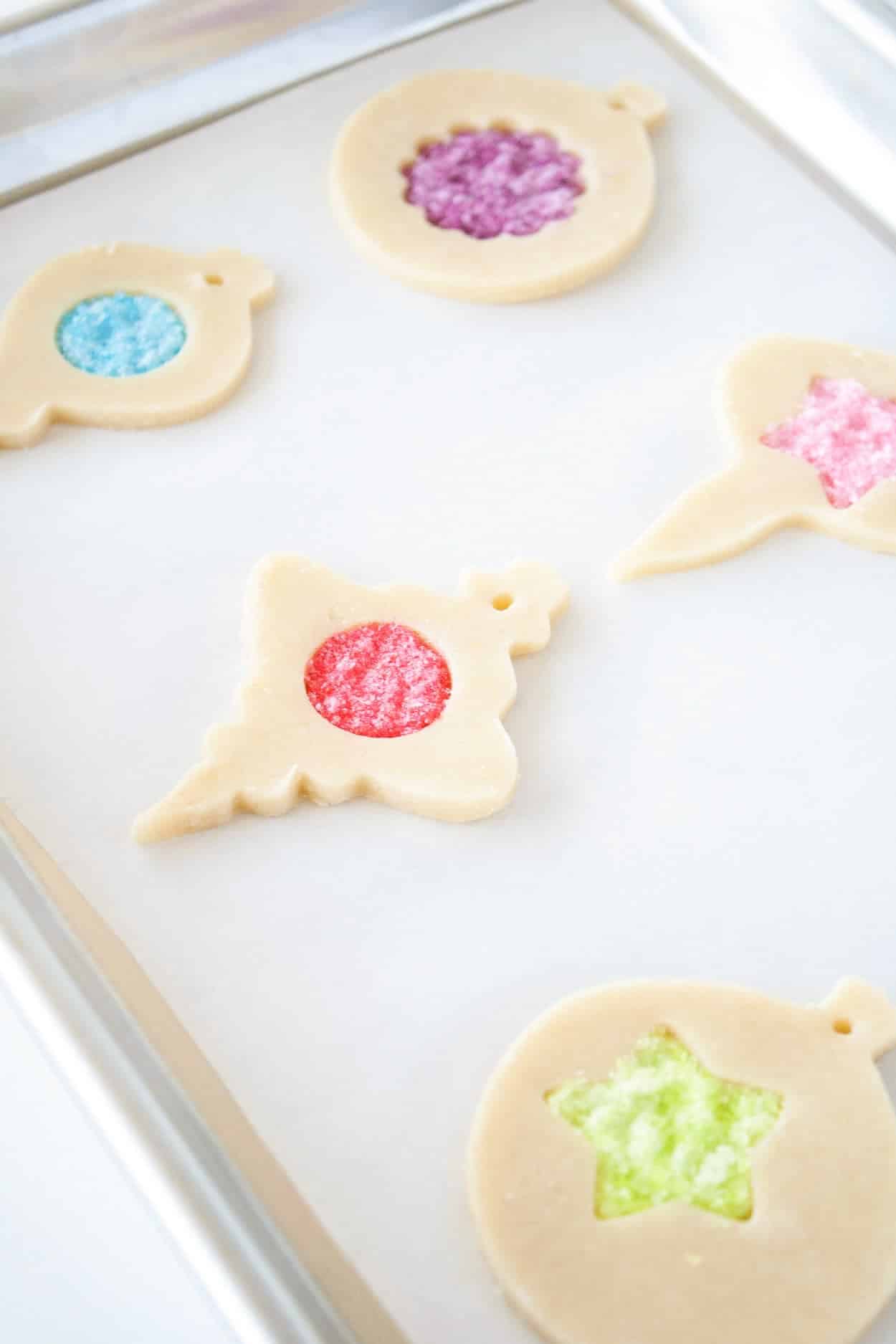 Unbaked stained glass cookies on a cookie sheet