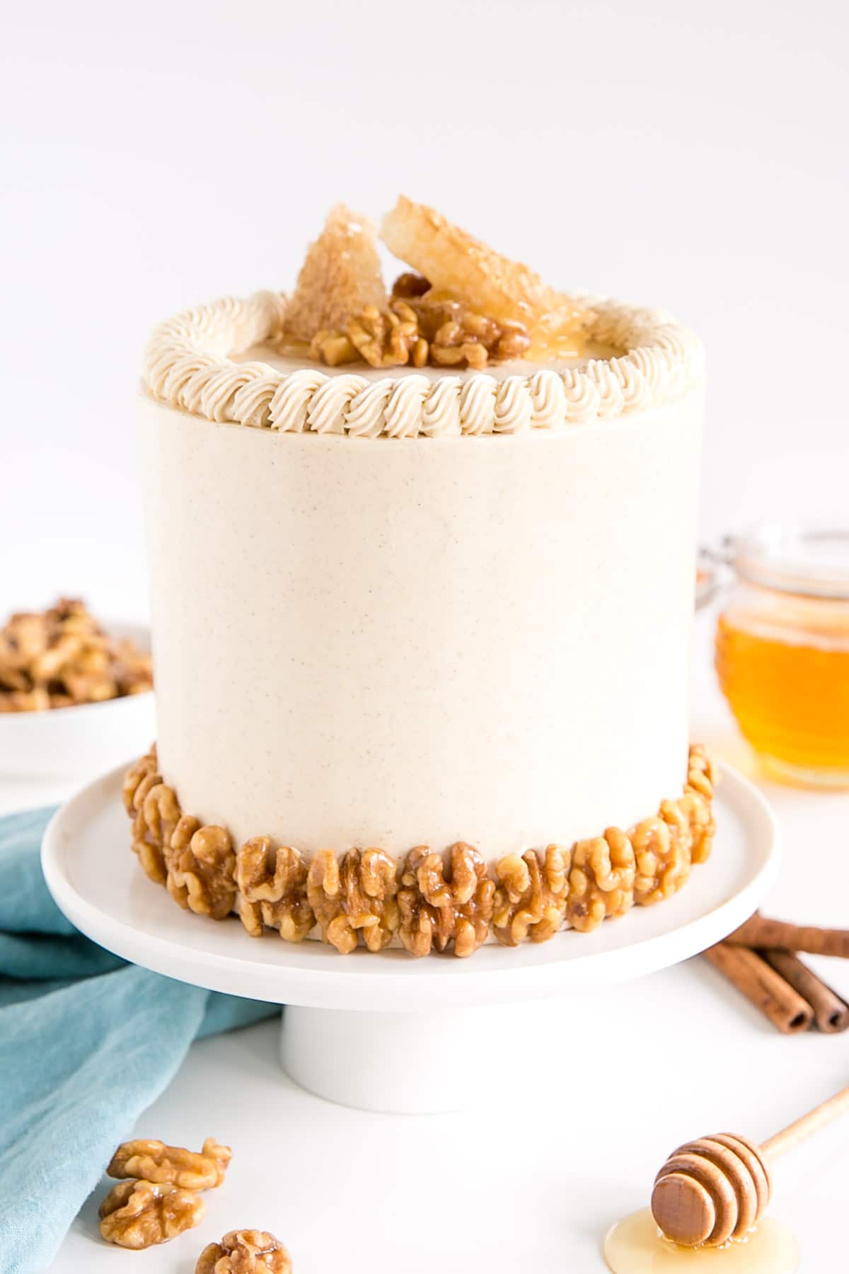 Cake on a white cake stand. Honey walnuts along the bottom and honeycomb on the top.