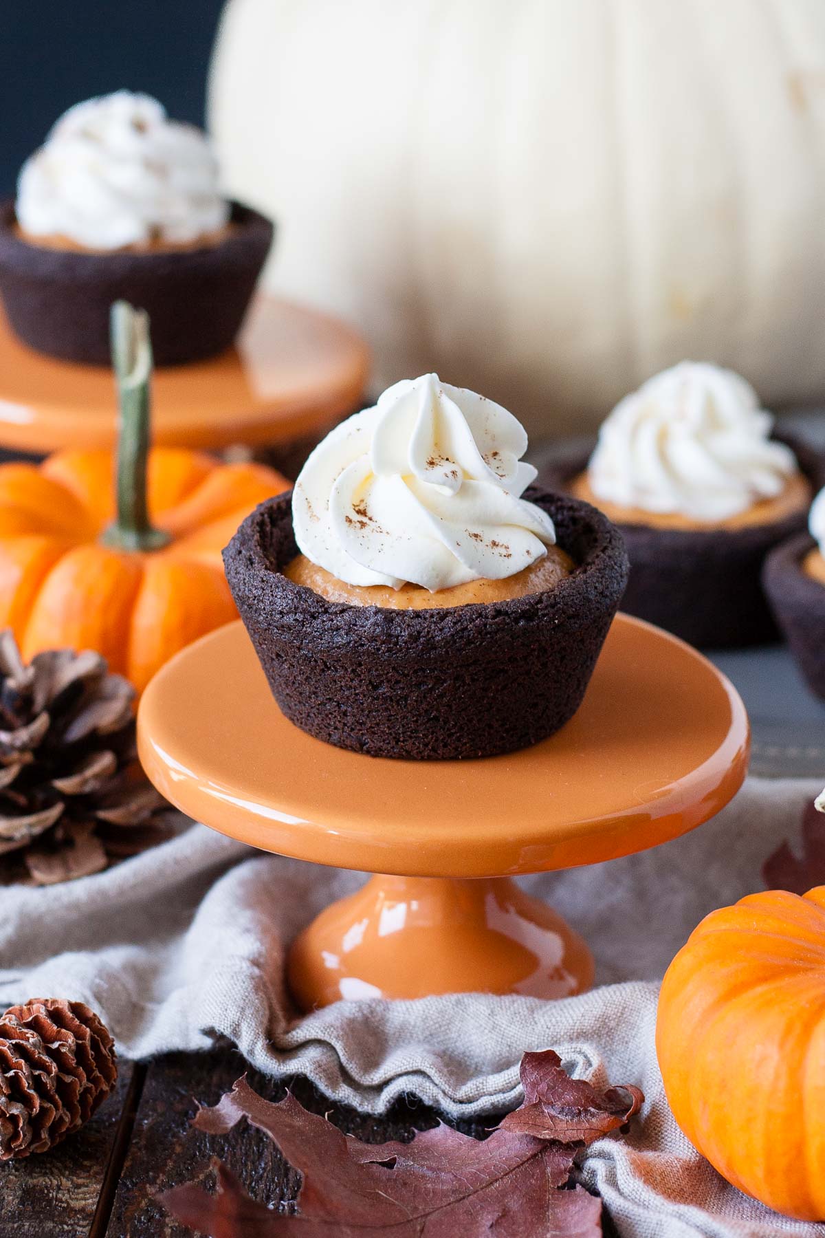 Cookie cup topped with whipped cream on a small orange cupcake stand.