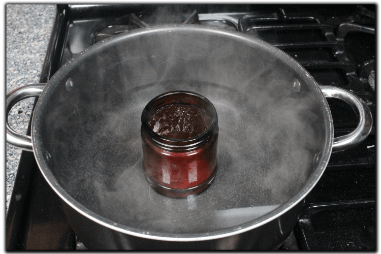 candle sitting in hot water to melt old wax off