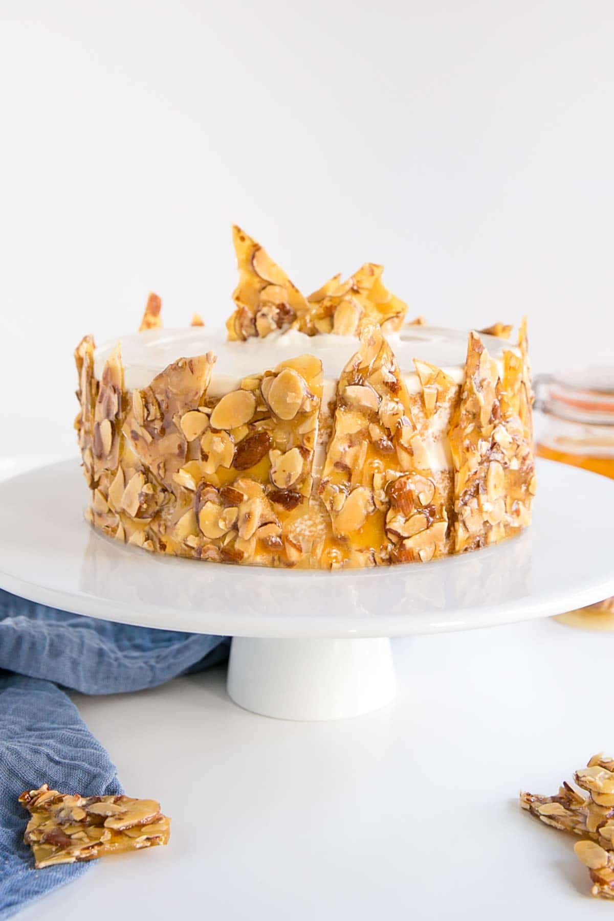 Honey Almond cake on a white cake stand with a blue cloth under it.