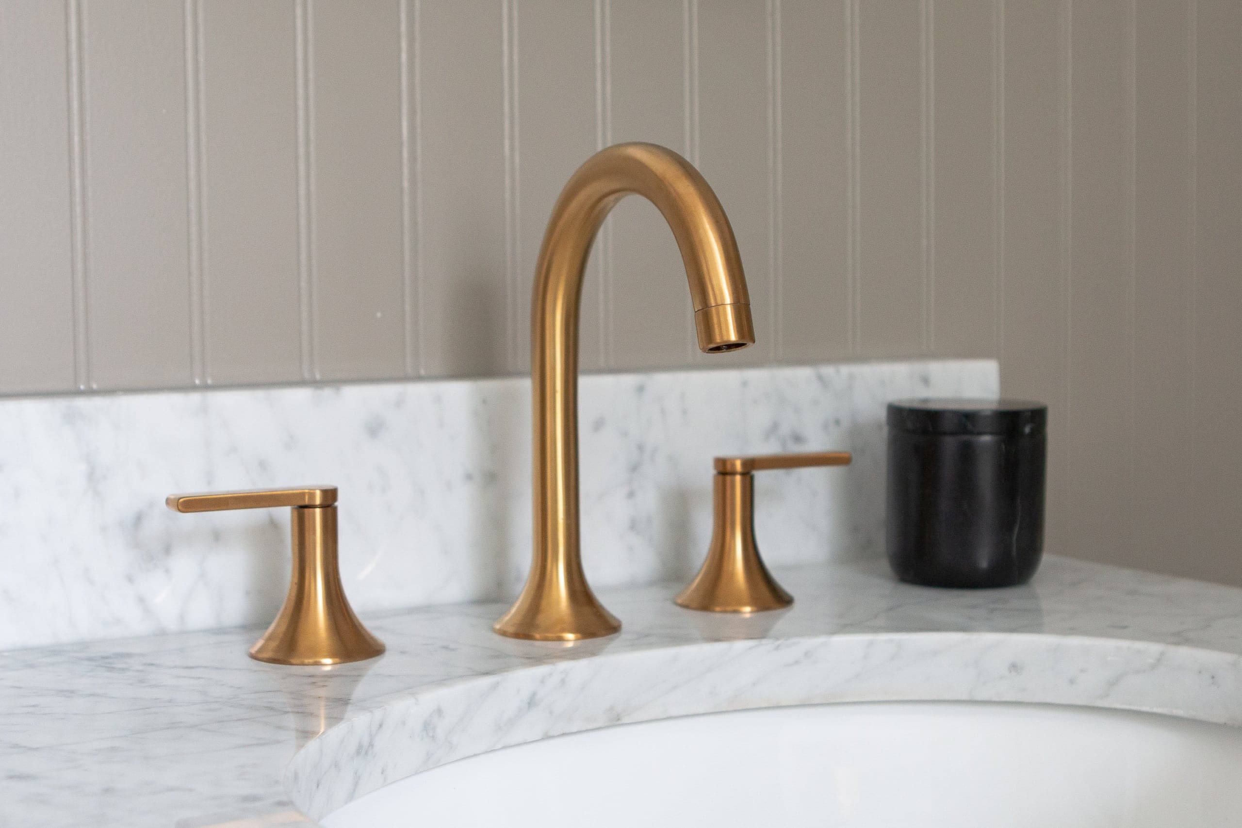 A gold faucet in a marble vanity