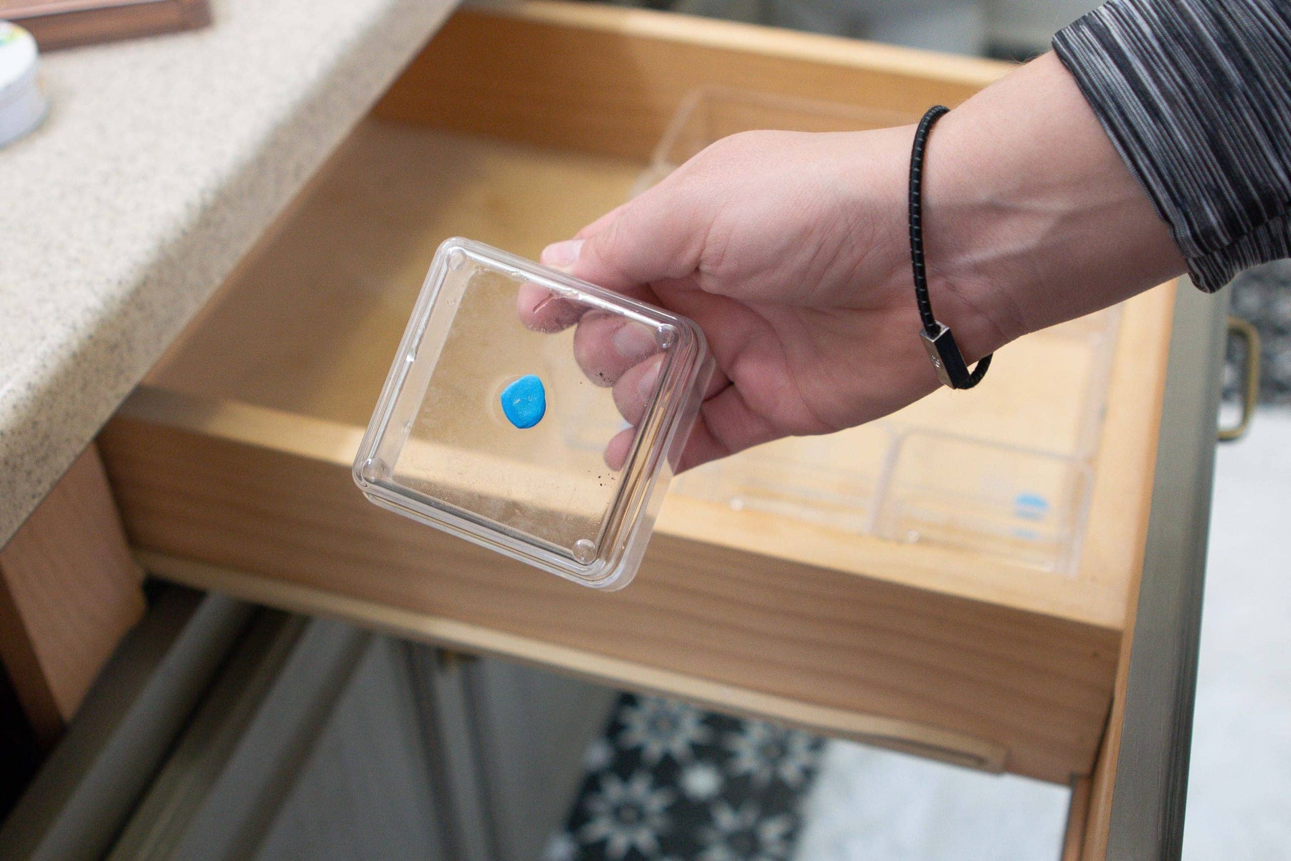 Sticky putty on the back of clear makeup containers