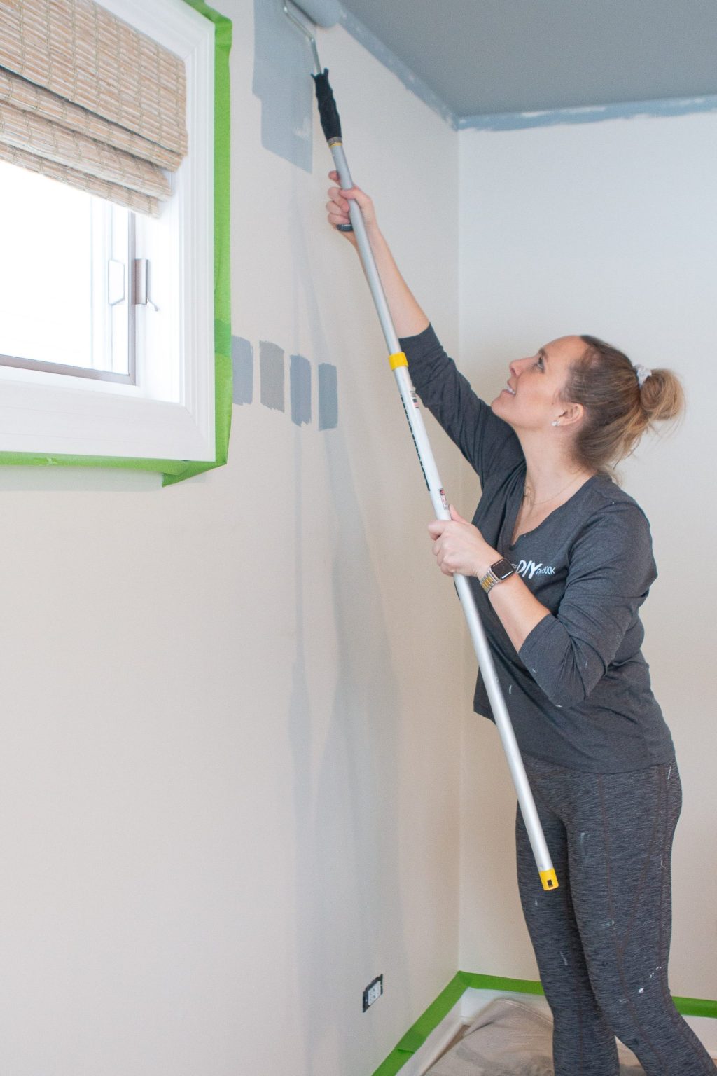 Using a paint roller to paint the room