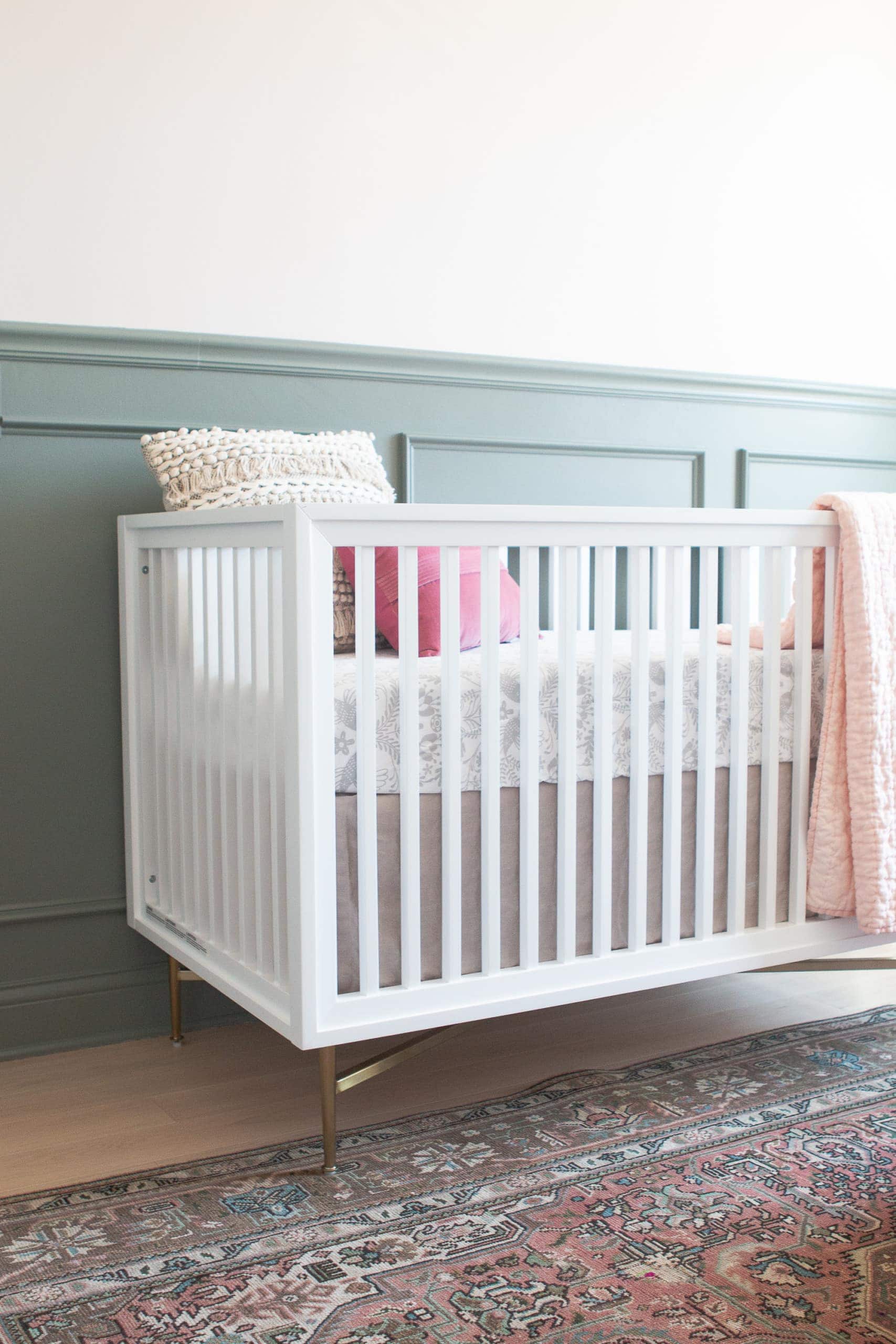 White crib against sage green chair rail