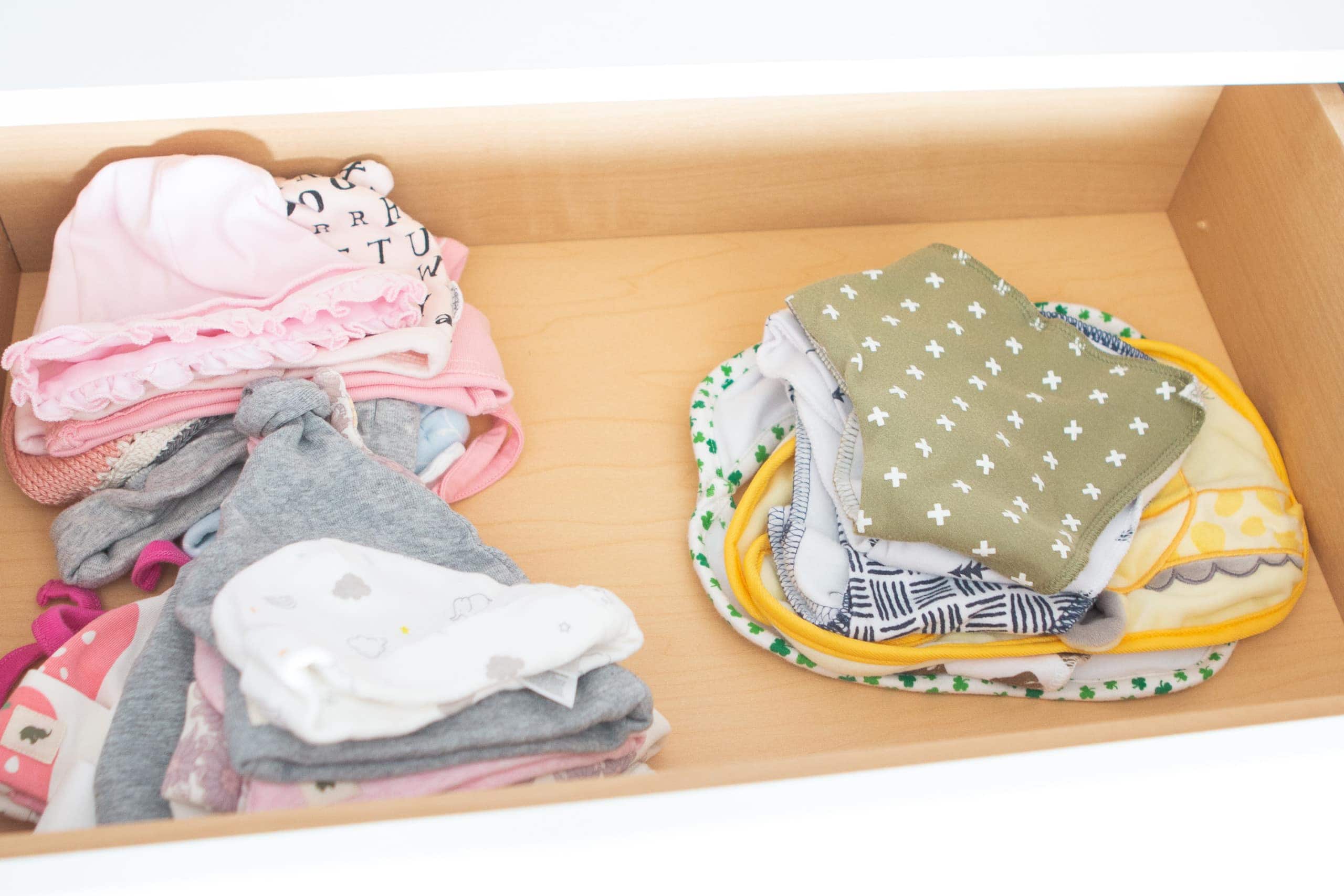 Filling up a baby drawer with hats and burp cloths
