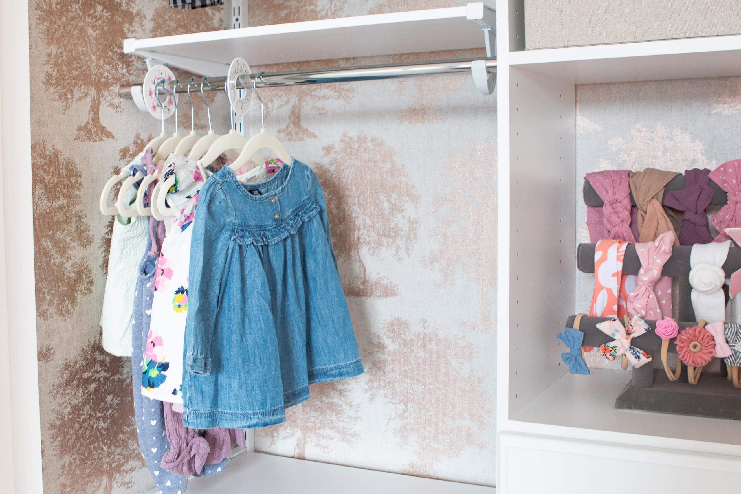 Hanging baby clothes in an organized nursery closet