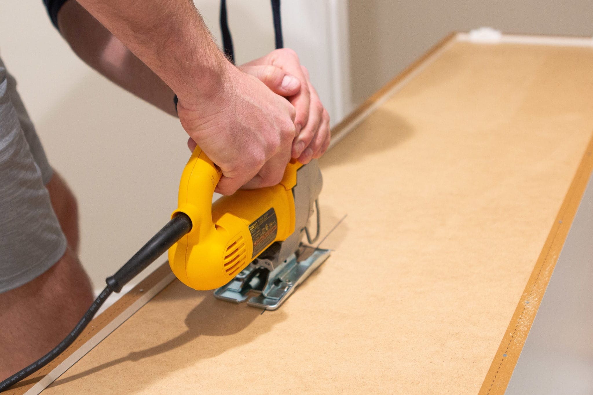 Using a jigsaw to cut out the back of a cabinet