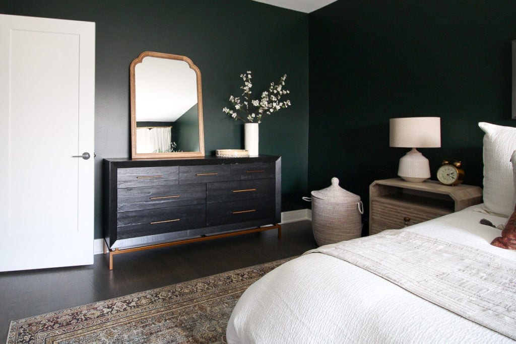 Dark green guest room with Black dresser with mirror