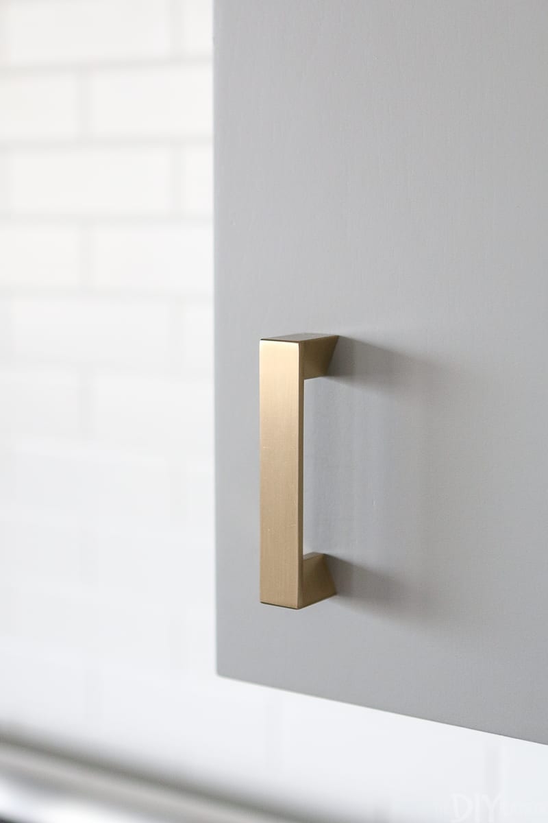 Gold hardware on a gray kitchen cabinet