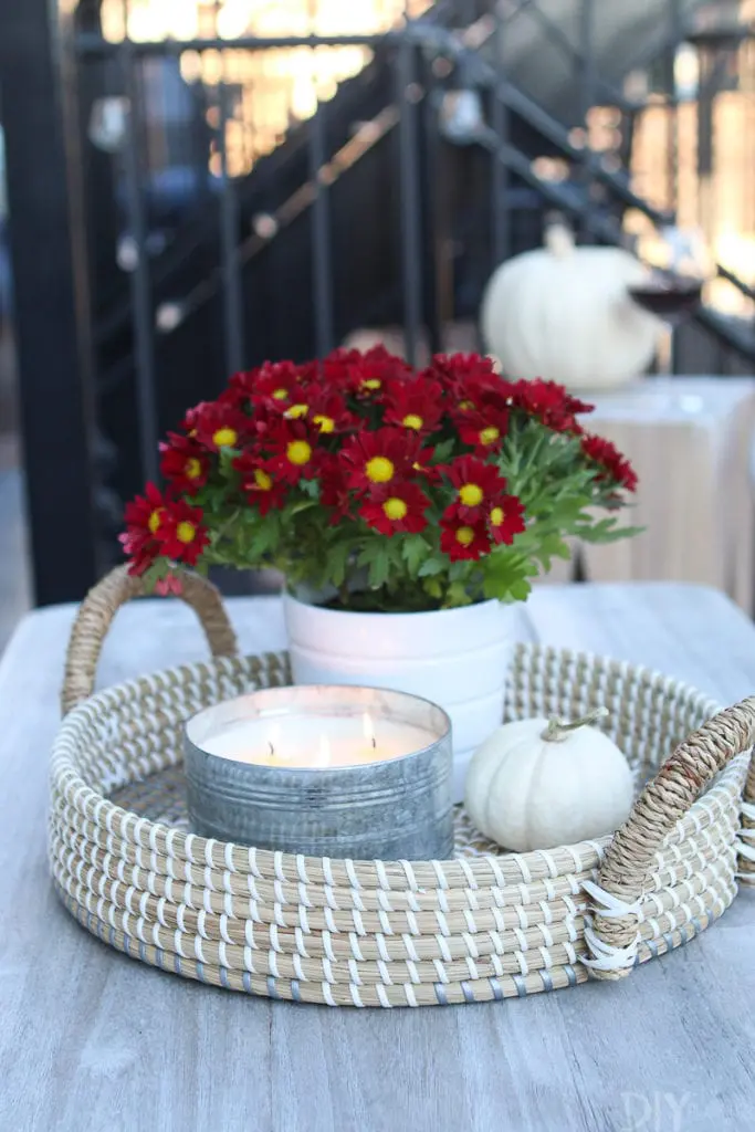 A coffee table with a tray, candle, and mini pumpkin