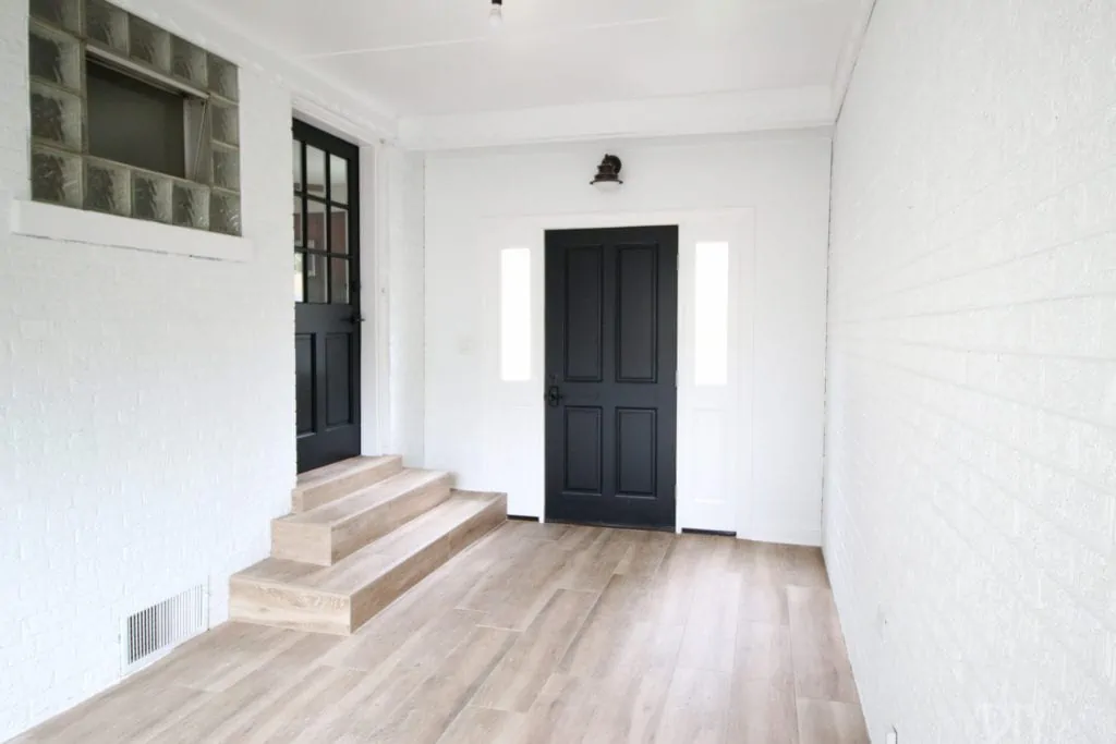 A white and black mudroom with faux wood tile