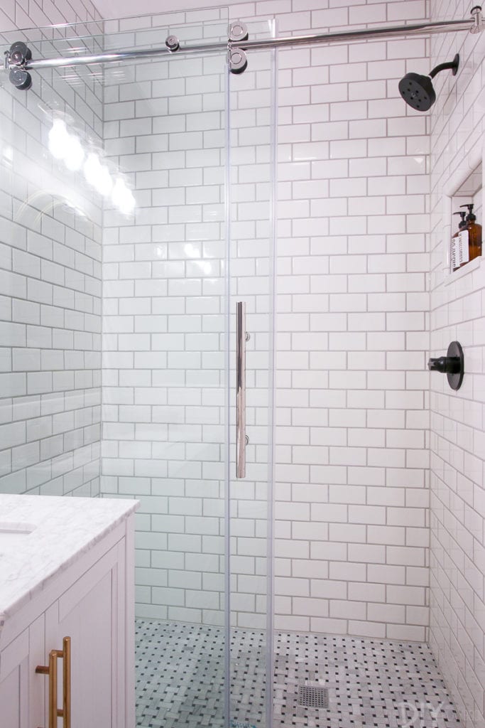 Glass shower doors show off the new subway tile in this bathroom makeover