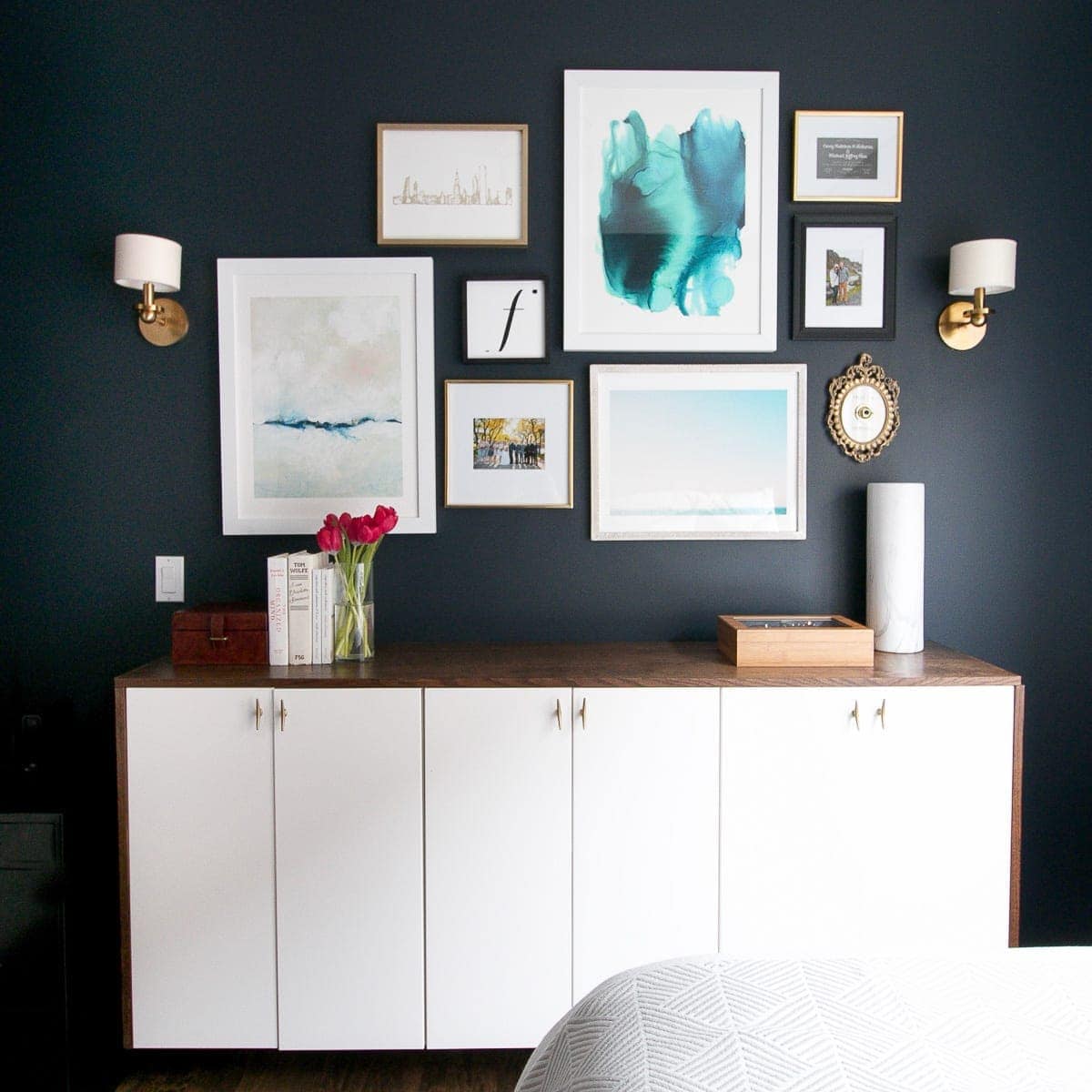 A navy guest room with a gallery wall of frames. 