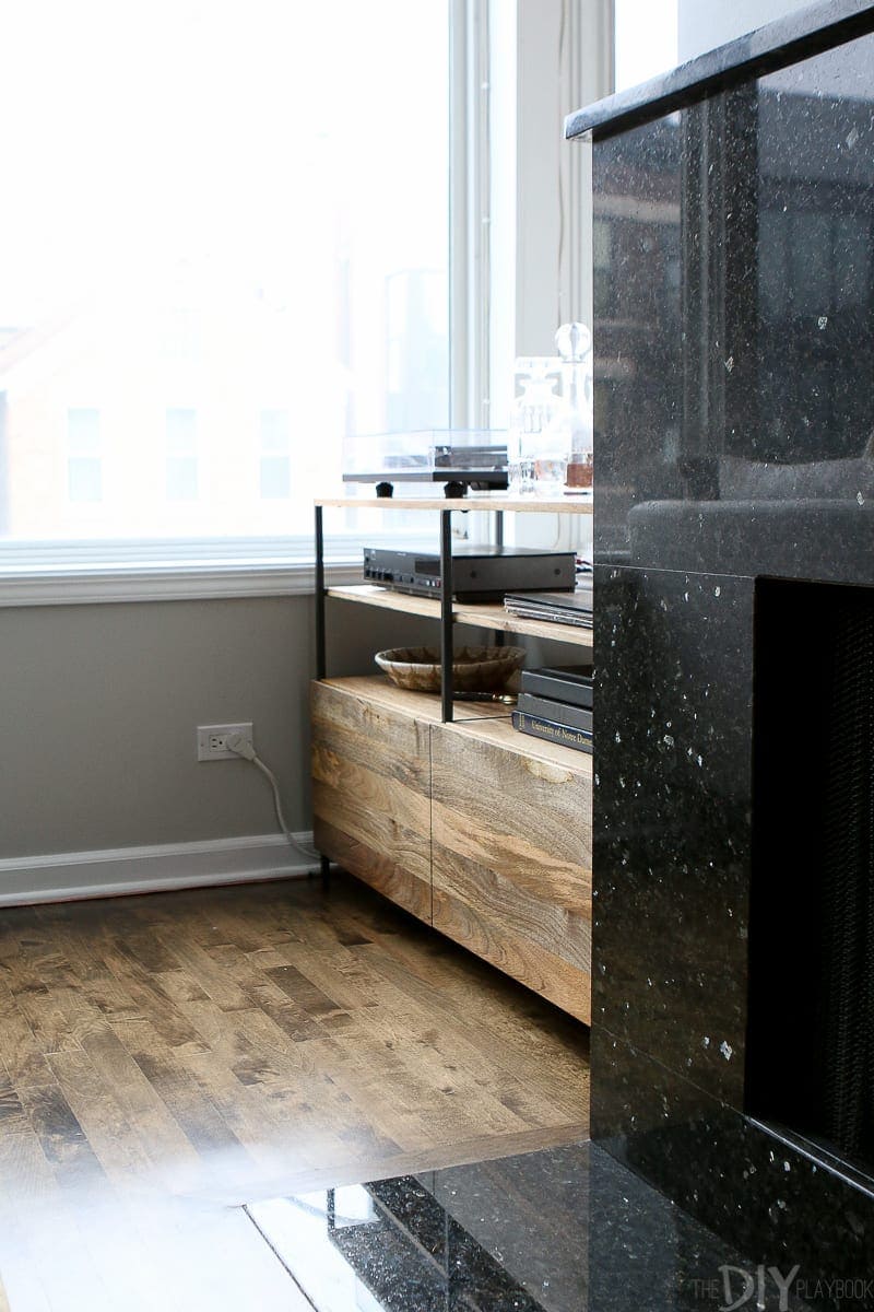 A wood entertainment center from West Elm holds records and a record player. 