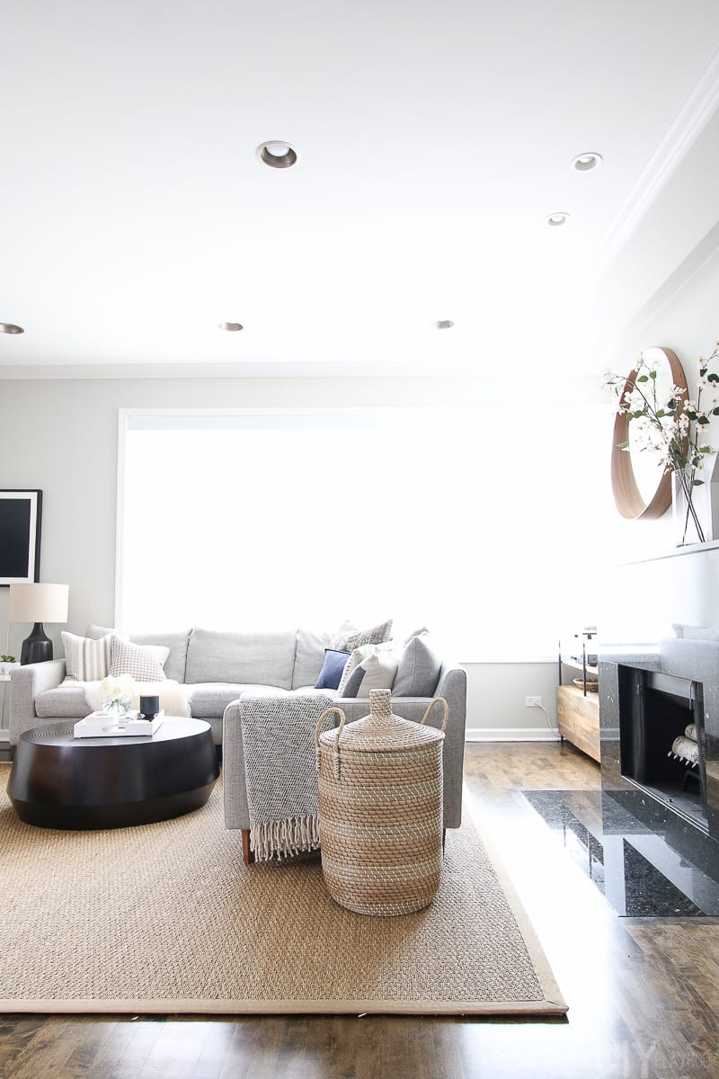 A gray sectional with the fireplace behind the couch. 