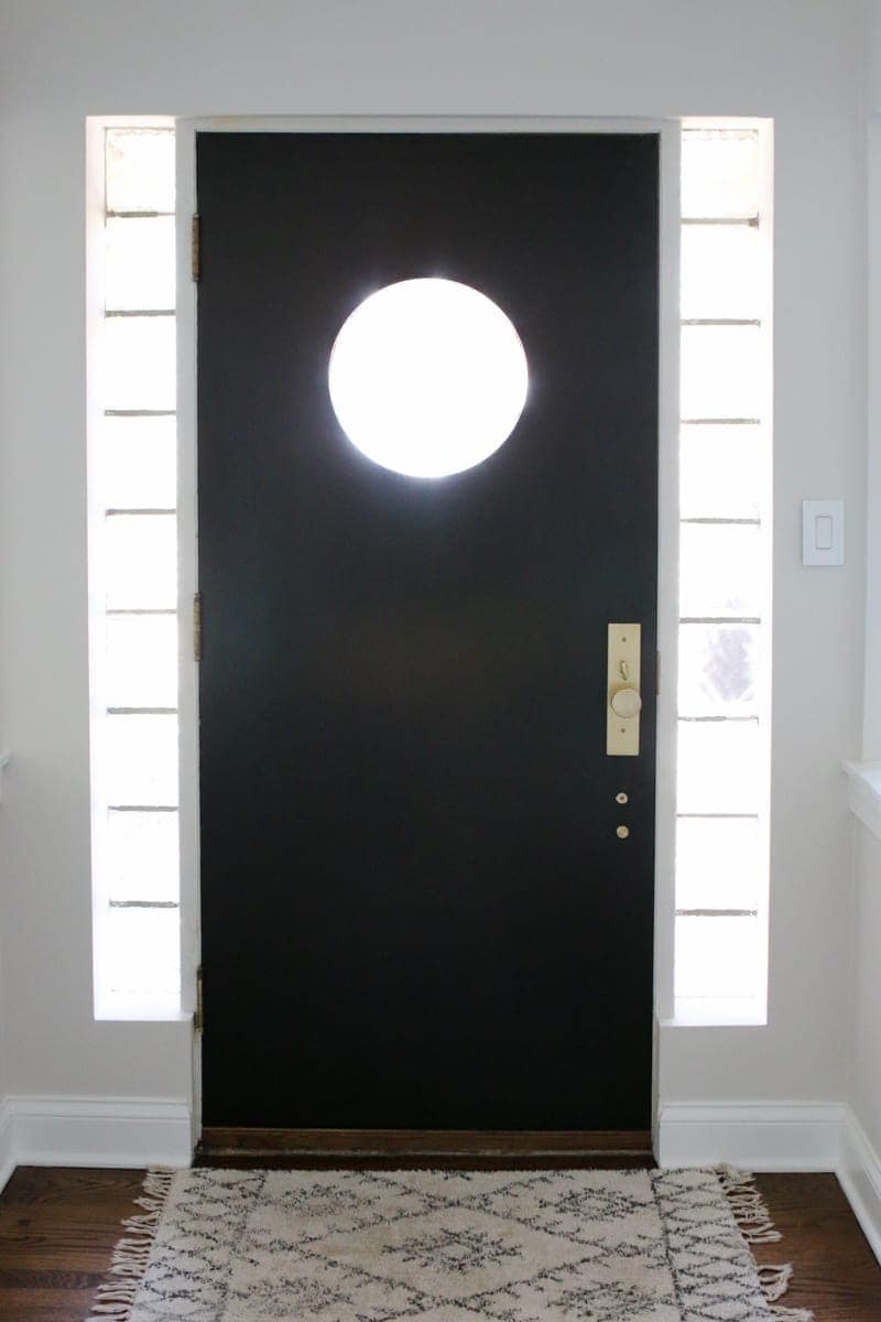 A black front door with satin brass hardware makes a statement in this bright home