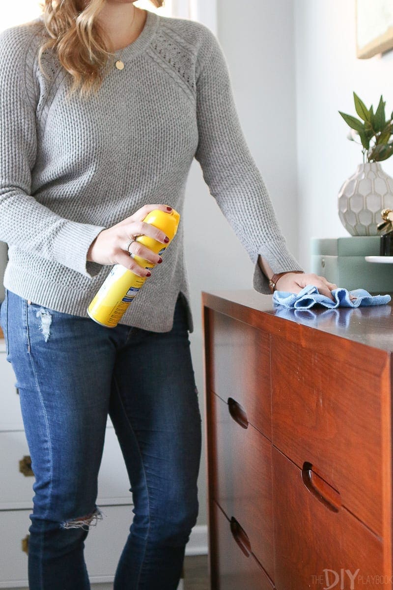 Dusting a dresser with pledge and a cloth to get your house clean. 