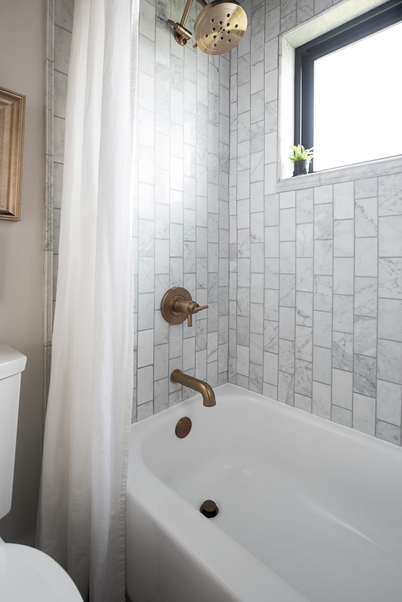 Marble tile with gold shower head and fixtures. 