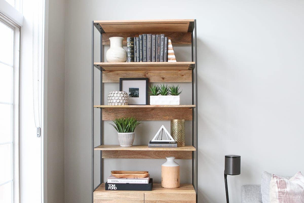 Tips to style bookshelves. Fill them with books, accessories, and greenery for a styled look. 