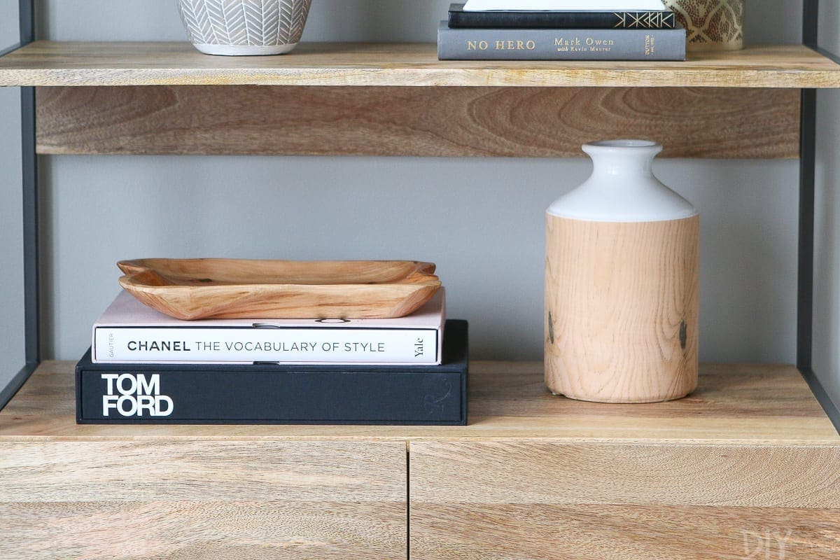 A bookshelf decorated with vases and coffee table books. 