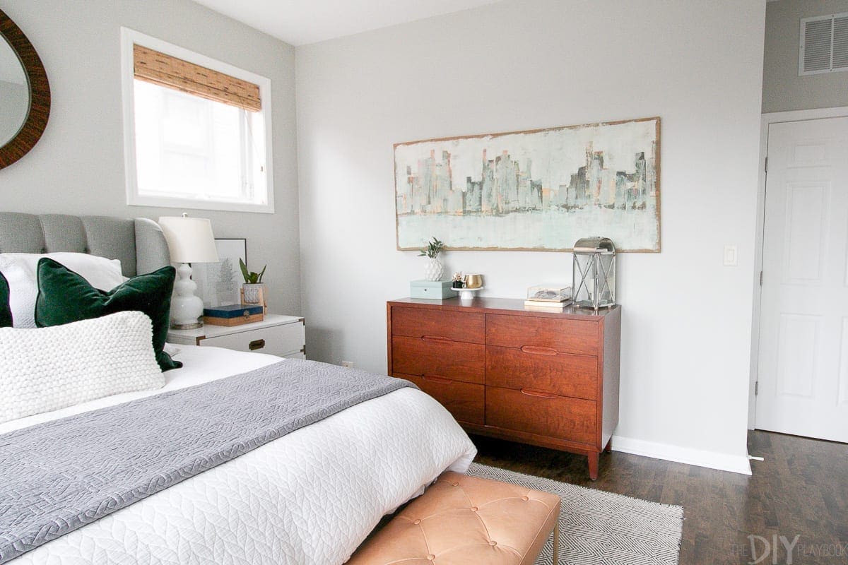 Gray master bedroom with blue art and wood touches