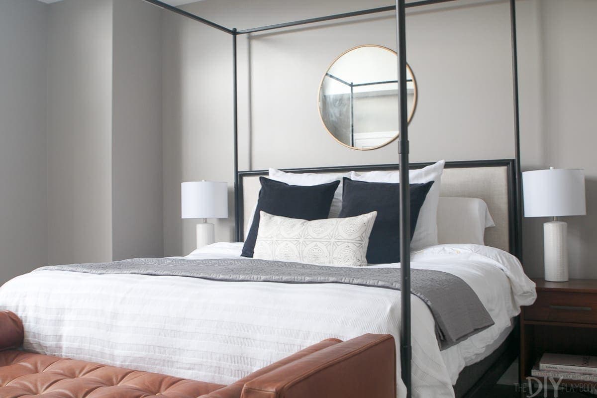 master bedroom queen size bed details. White bed linens with black and white pillows and a gray blanket. 