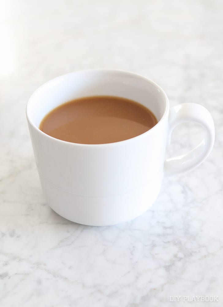 A plain white mug with coffee and creamer. 