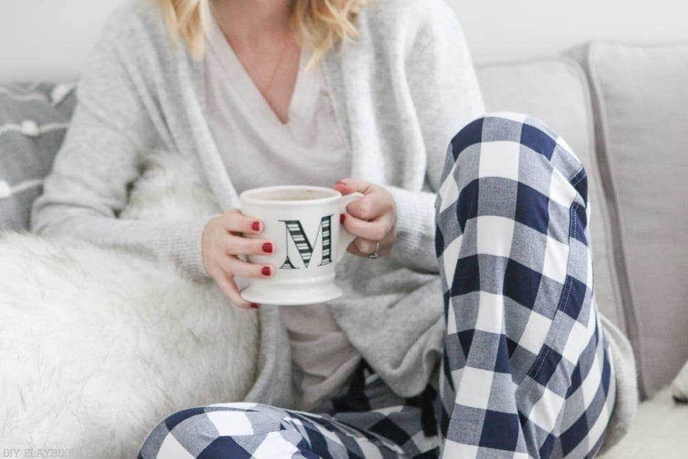 Coffee in the morning. Bridget on the couch with plaid pajama pants and a mug with the letter M on it.