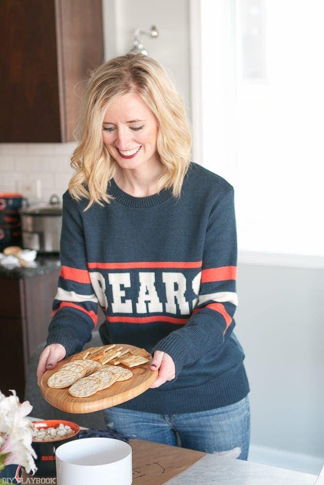 Bridget loves her Chicago Bears (at least she loves this Chicago Bears sweater she is sporting!) She's getting the crackers ready to offer the football party guests. 