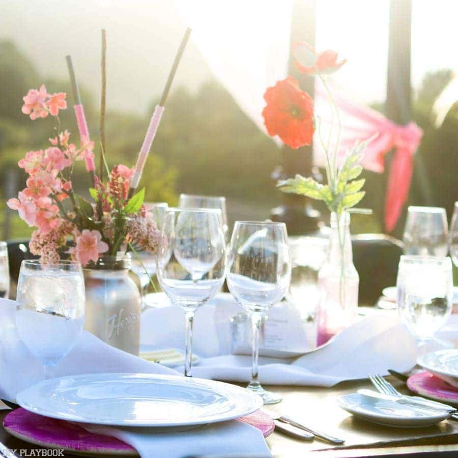 Beautiful tablescape with poppies and bright flowers next to white dishes. 