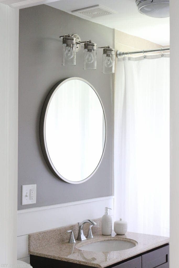 Bathroom with grey accent wall above the vanity and silver accents on the fixtures.