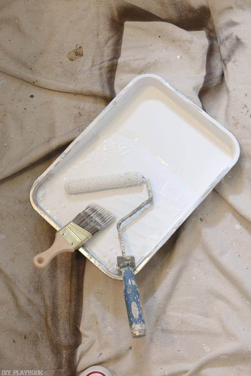 Paint brushes, a tray, and white paint were used to paint the shiplap wall.