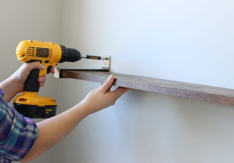 Hanging a shelf using a DeWalt drill. 