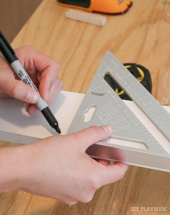 Using a speed square to mark the measurements on the wood. 