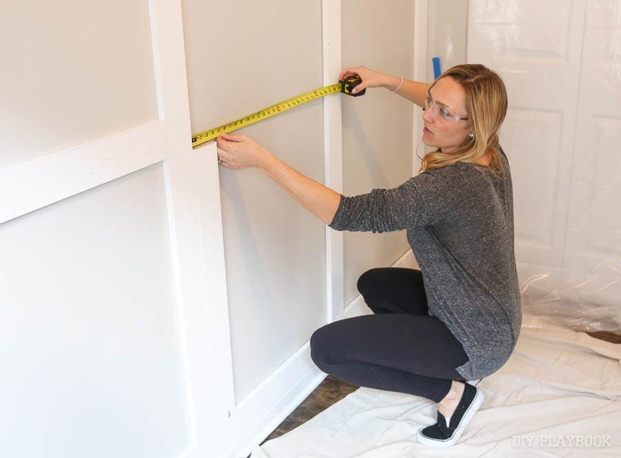 Casey using a tape measure to ensure the boards are hung straight.