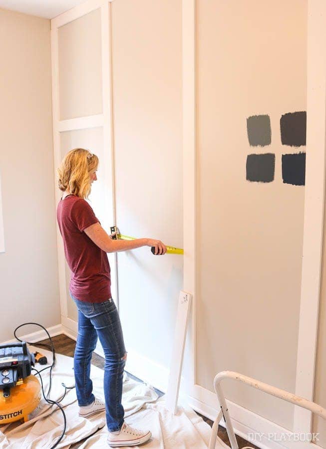 Bridget measuring the wall exactly before installing the horizontal boards on the wall. 