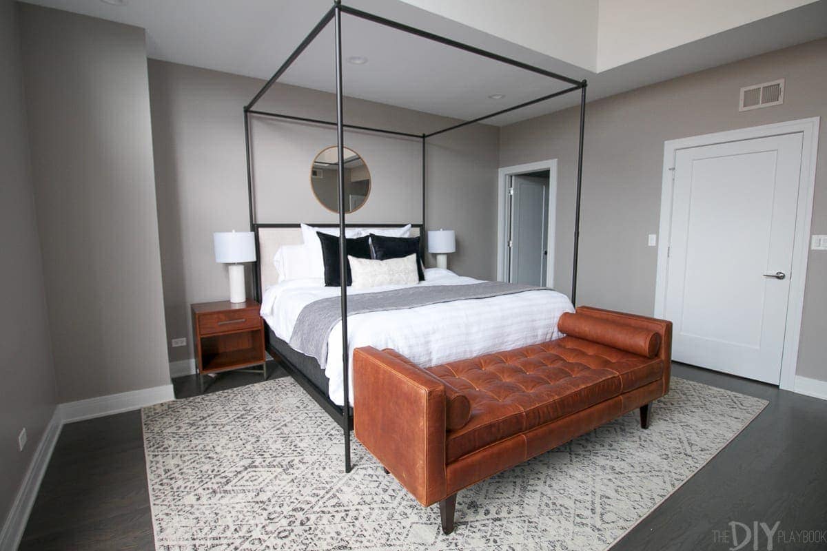 This modern master bedroom design looks so sleek and sophisticated with the gray and black color scheme. The pops of brown from the bench and nightstands give the room a warm touch. 