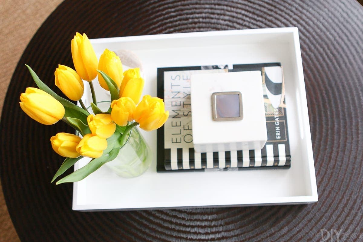 A white tray on a black coffee table. 