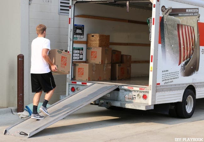 Casey's husband loads a box onto the U-Haul. 