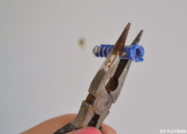 First step in patching holes in your wall is pulling out any old anchors used to hang shelves or photos. 