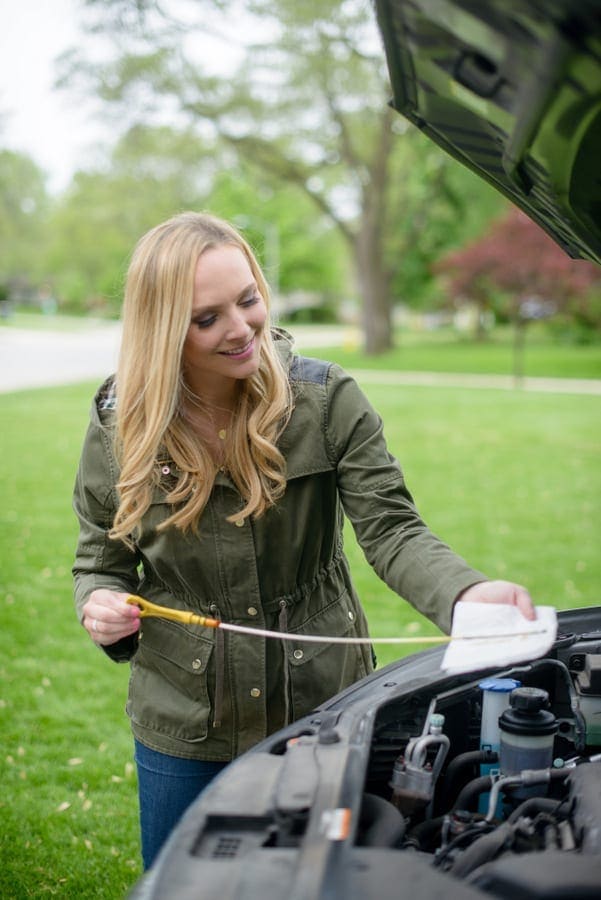 Casey checks her car's oil.