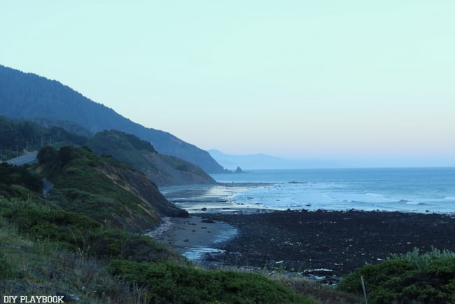 Green hills and blue water along a rocky beach along Highway 101, from our Seattle to San Francisco road trip.