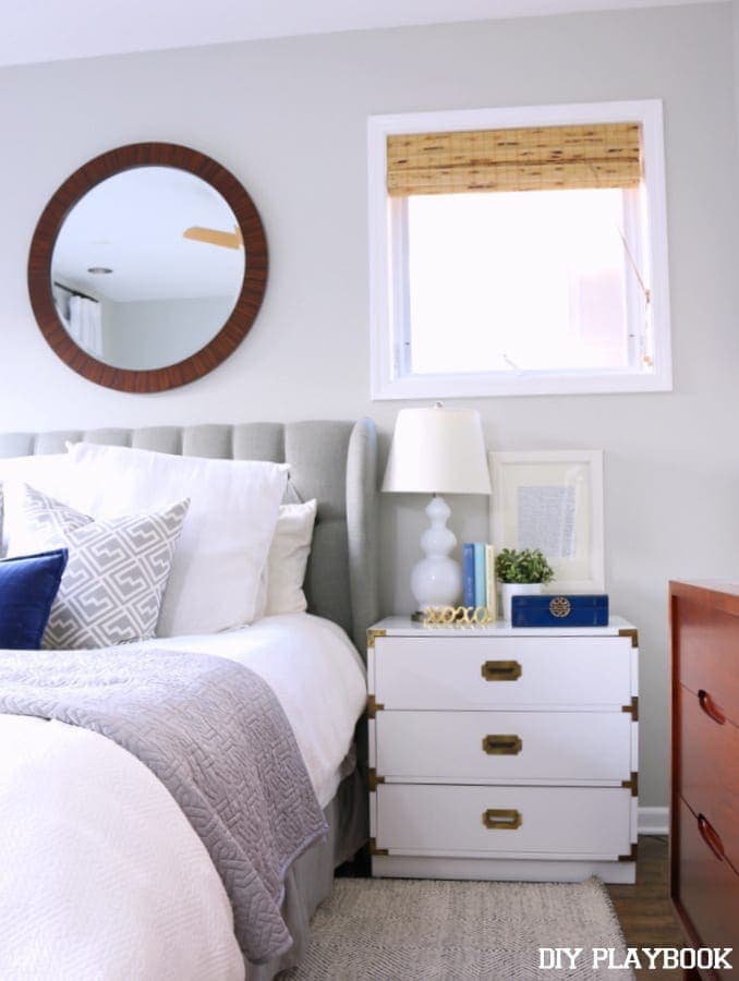 Nightstand under the small window with a bamboo shade. 