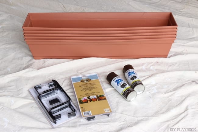 Assemble your materials for the flower boxes: plastic hardware store boxes, brackets, concrete anchors, and brown spray paint. 